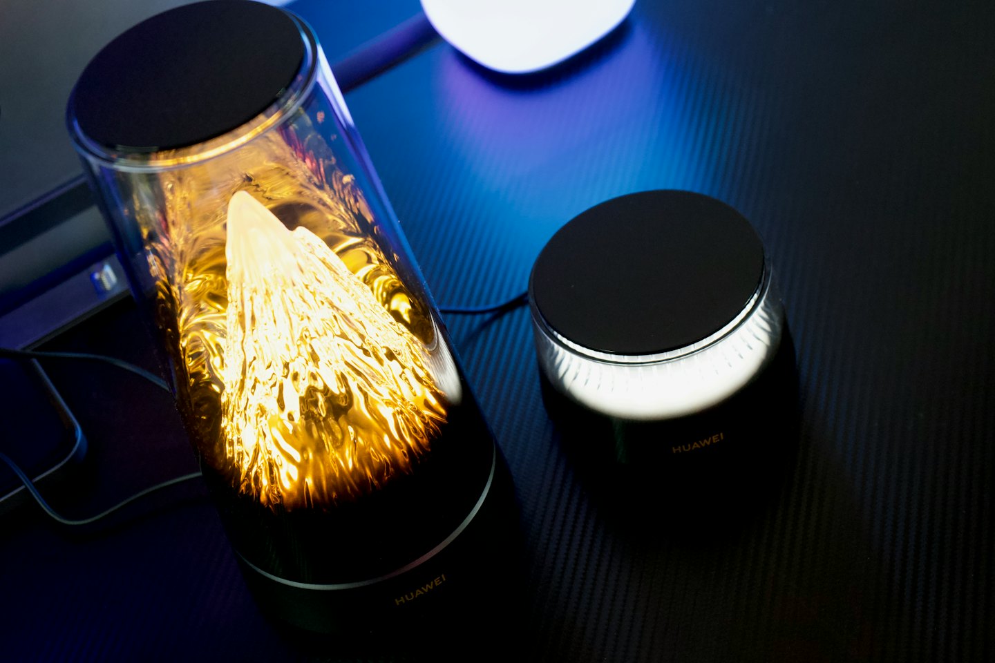 Two glowing electronic devices sit on a dark textured surface.