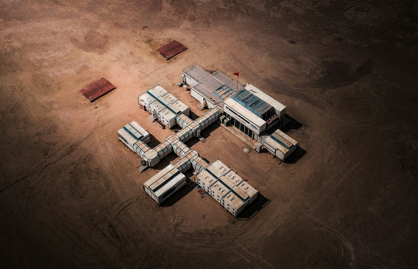 Modular research station with blue roofs in a desert.